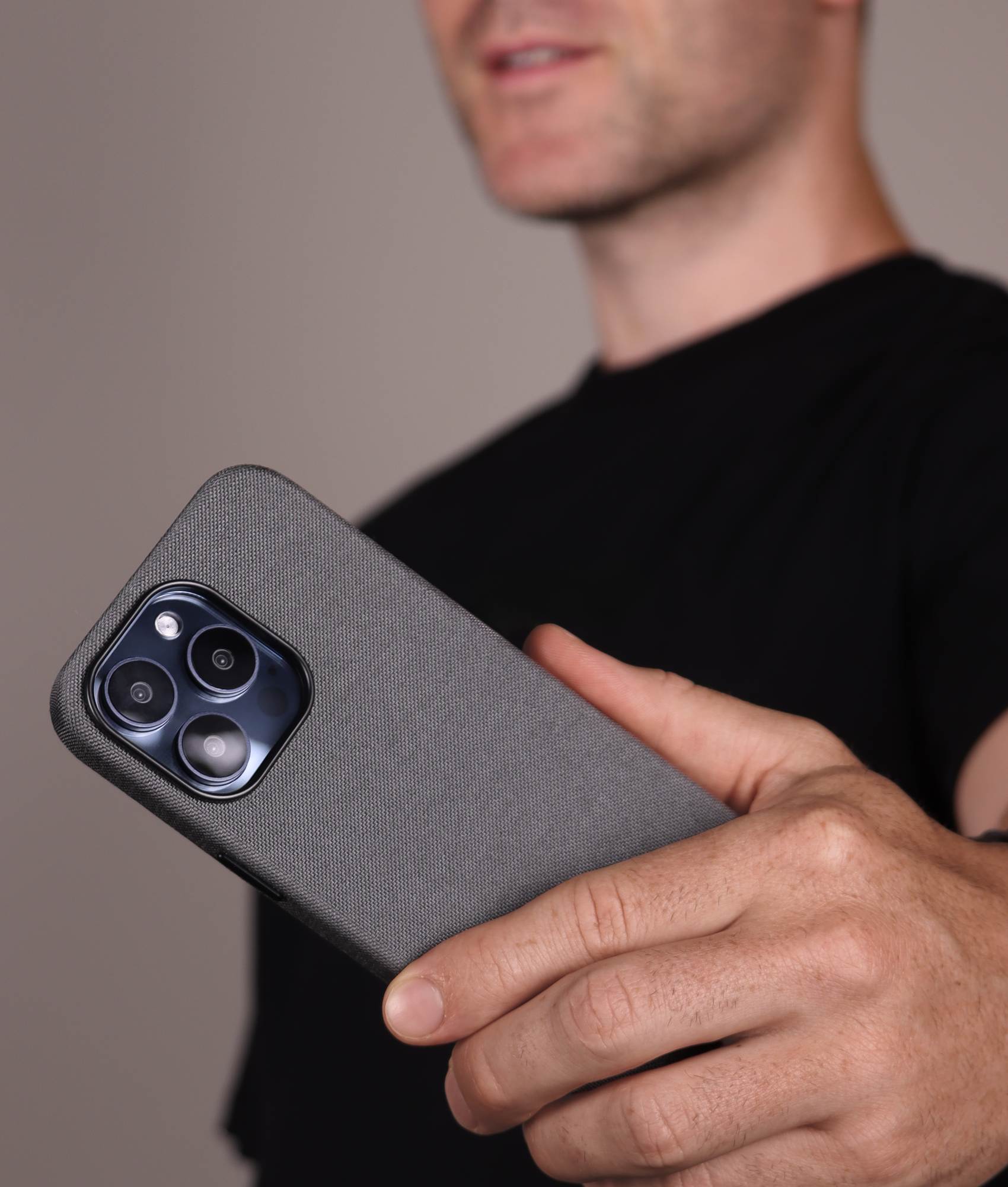 Komodoty Man in black tshirt holding iPhone with Kilimanjaro Cordura iPhone case in light grey 2000x1700