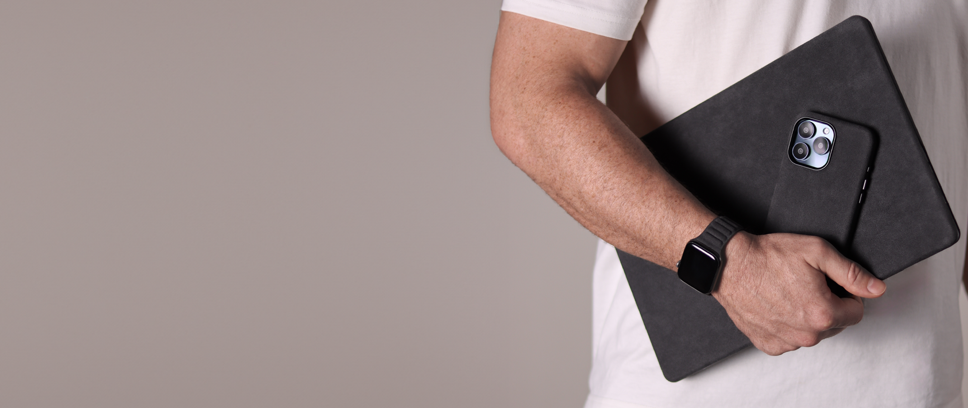 Komodoty Model in white t-shirt holding Saguaro Alcantara Italian Macbook Pro case, Alcantara iPhone  16 Pro Max Case and Alcantara Apple Watch band desktop banner 3200 x 1350