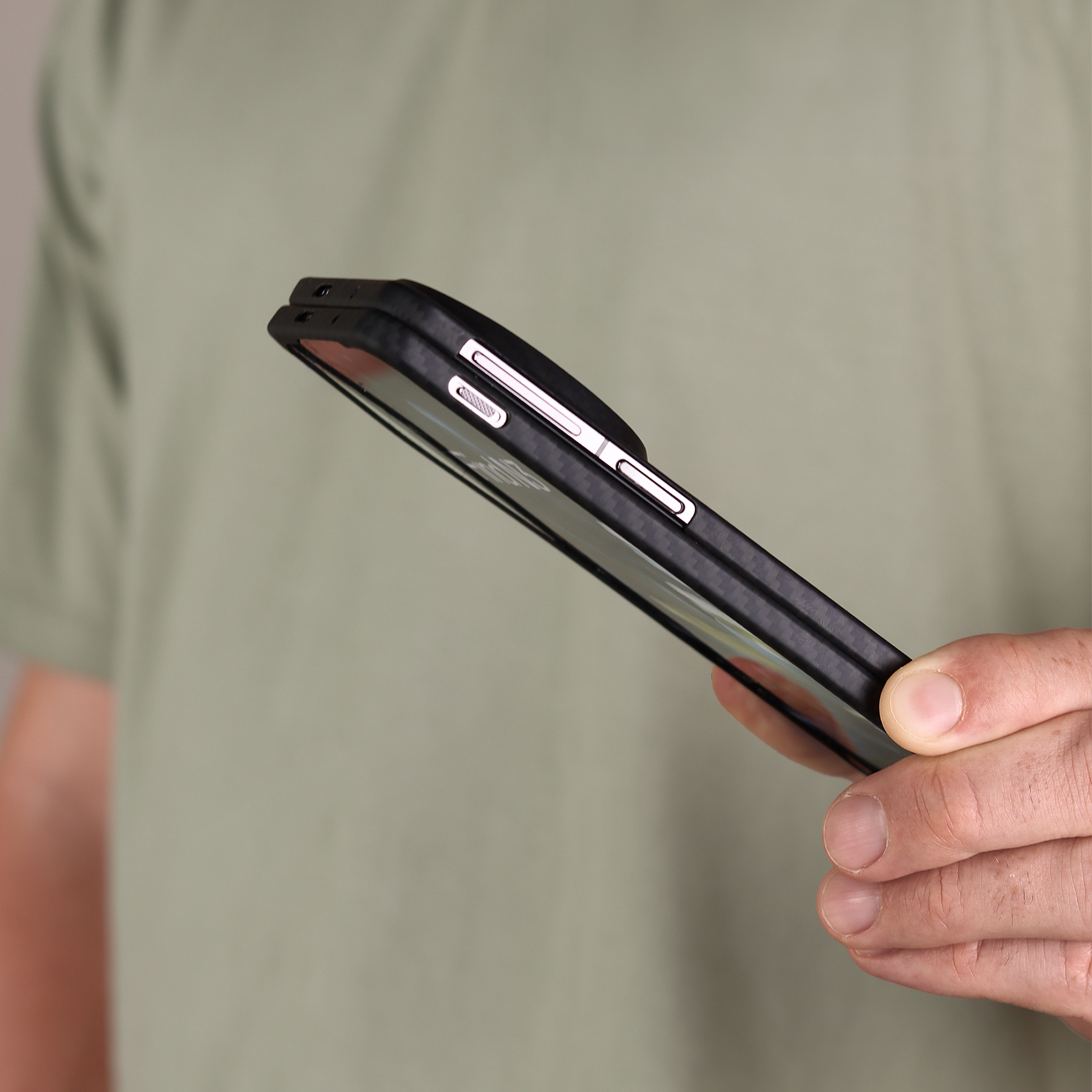 Komodoty Case Man holding a Volaris OnePlus 12 Slim with tshirt