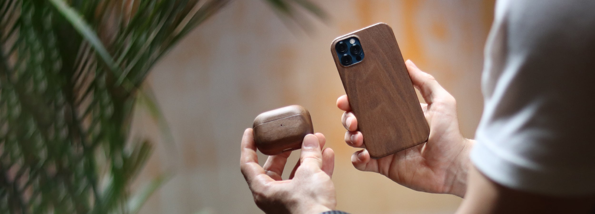 Komodoty man holding wood iPhone case and wood AirPods Case Walnut banner