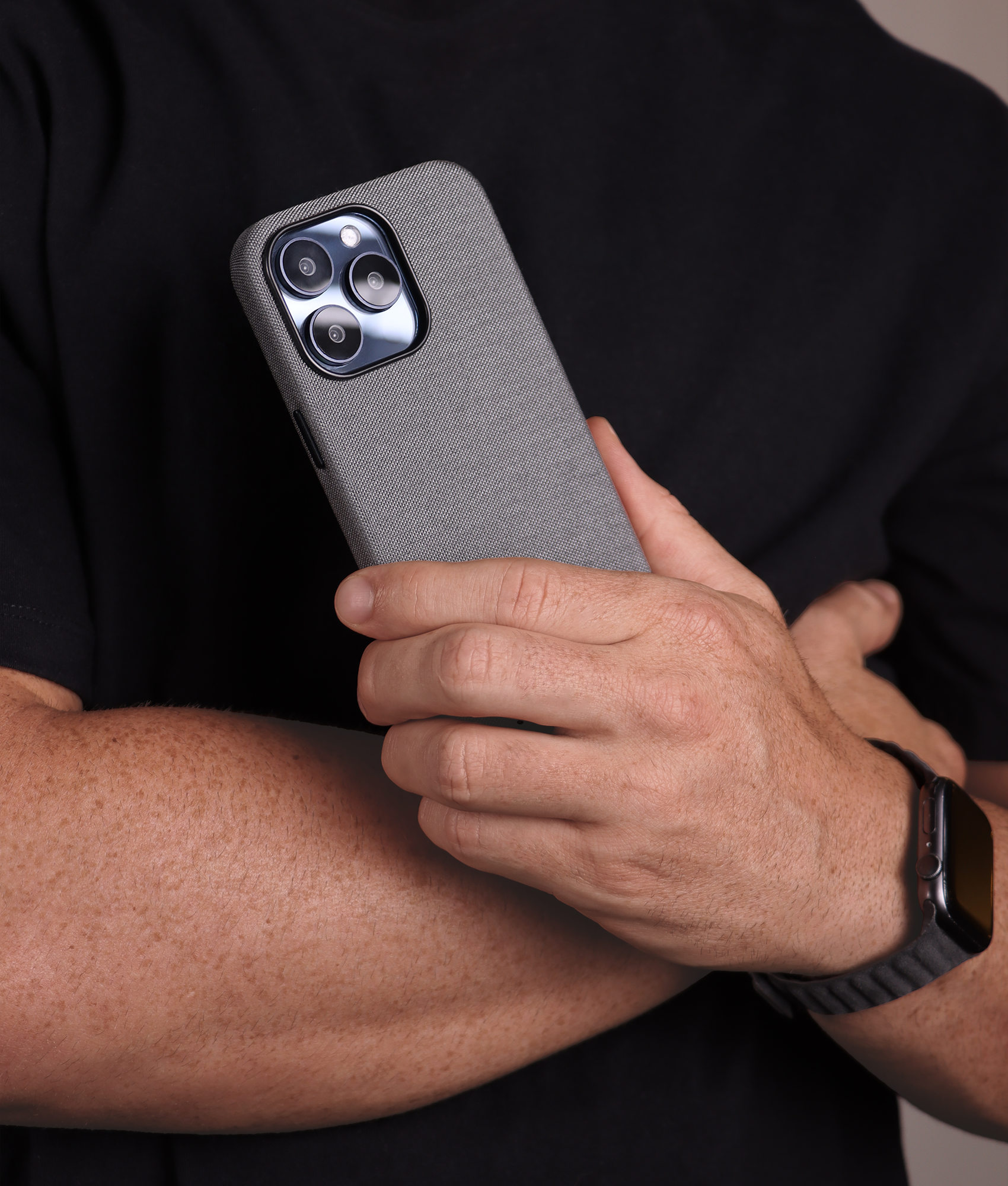 Komodoty Man in black tshirt holding iPhone with Kilimanjaro Cordura iPhone case in light grey with an Alcantara Apple Watch band in Black Alcantara (Komodoty's Saguaro) 2000x1700a