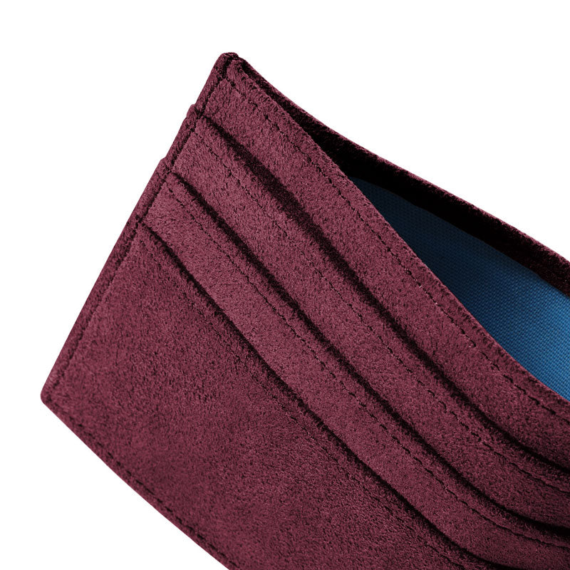 Burgundy Alcantara card wallet, macro close-up at an angle showing stitched card slots and suede texture, on a white background