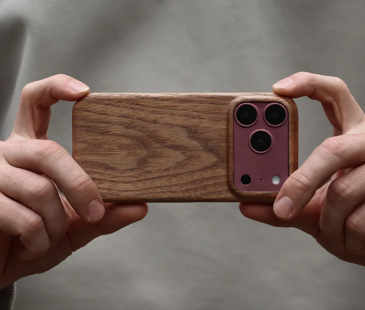 Man holding his iphone 18 pro in burgundy taking a photo with a walnut wood phone case