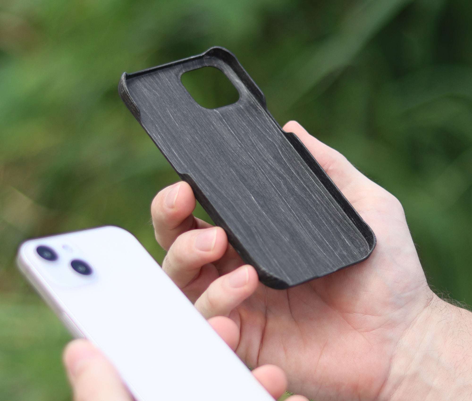 Komodoty man holding charcoal slim wood iPhone case showing inside